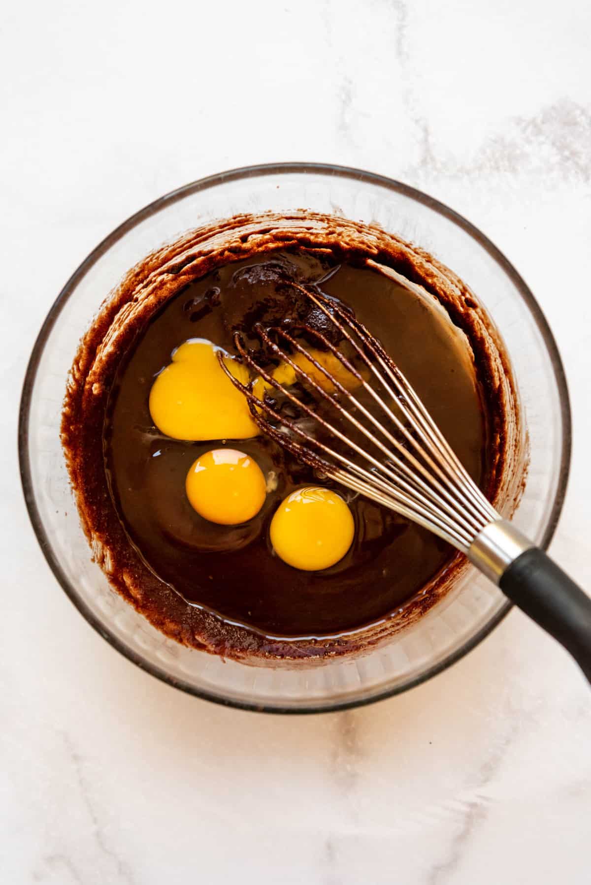 Adding eggs and vanilla extract to brownie batter.