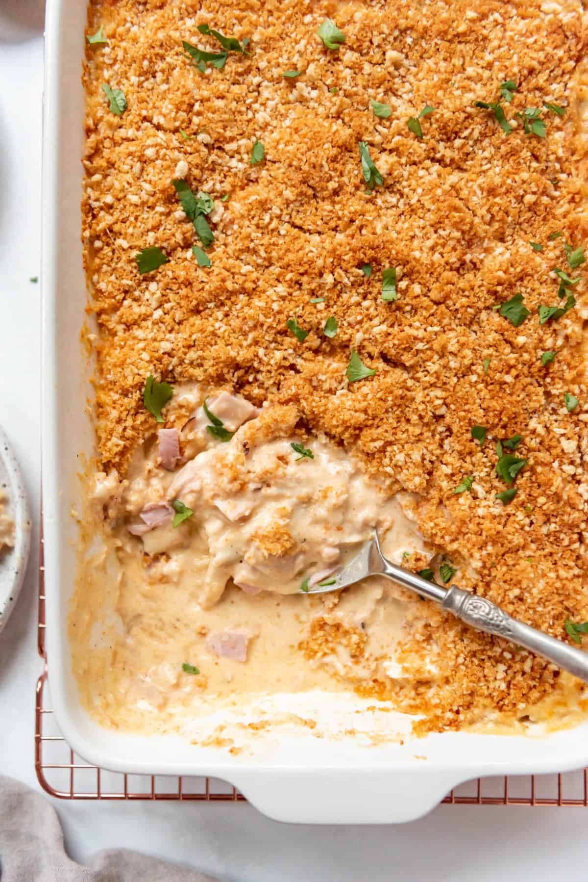 A large serving spoon in a baking dish of cordon bleu casserole.