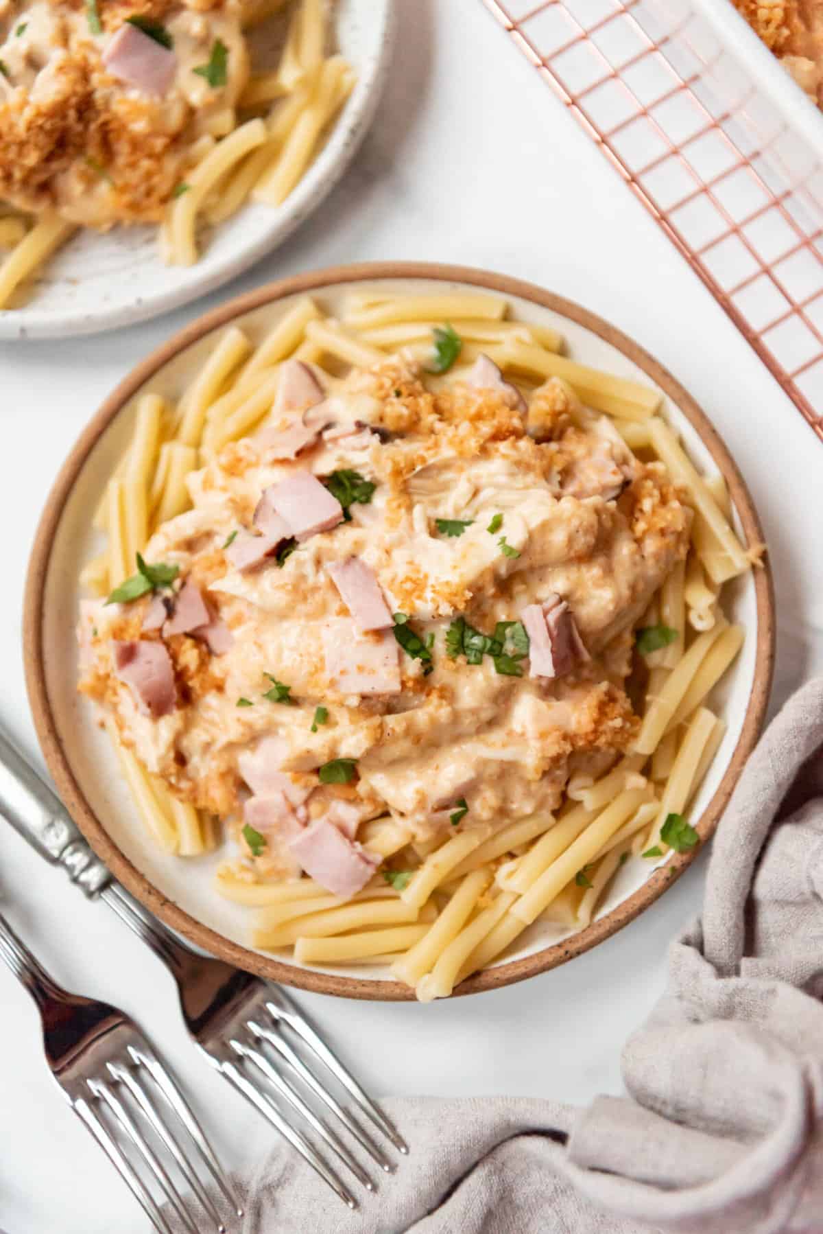 A large plate of chicken cordon bleu casserole served over cooked pasta.
