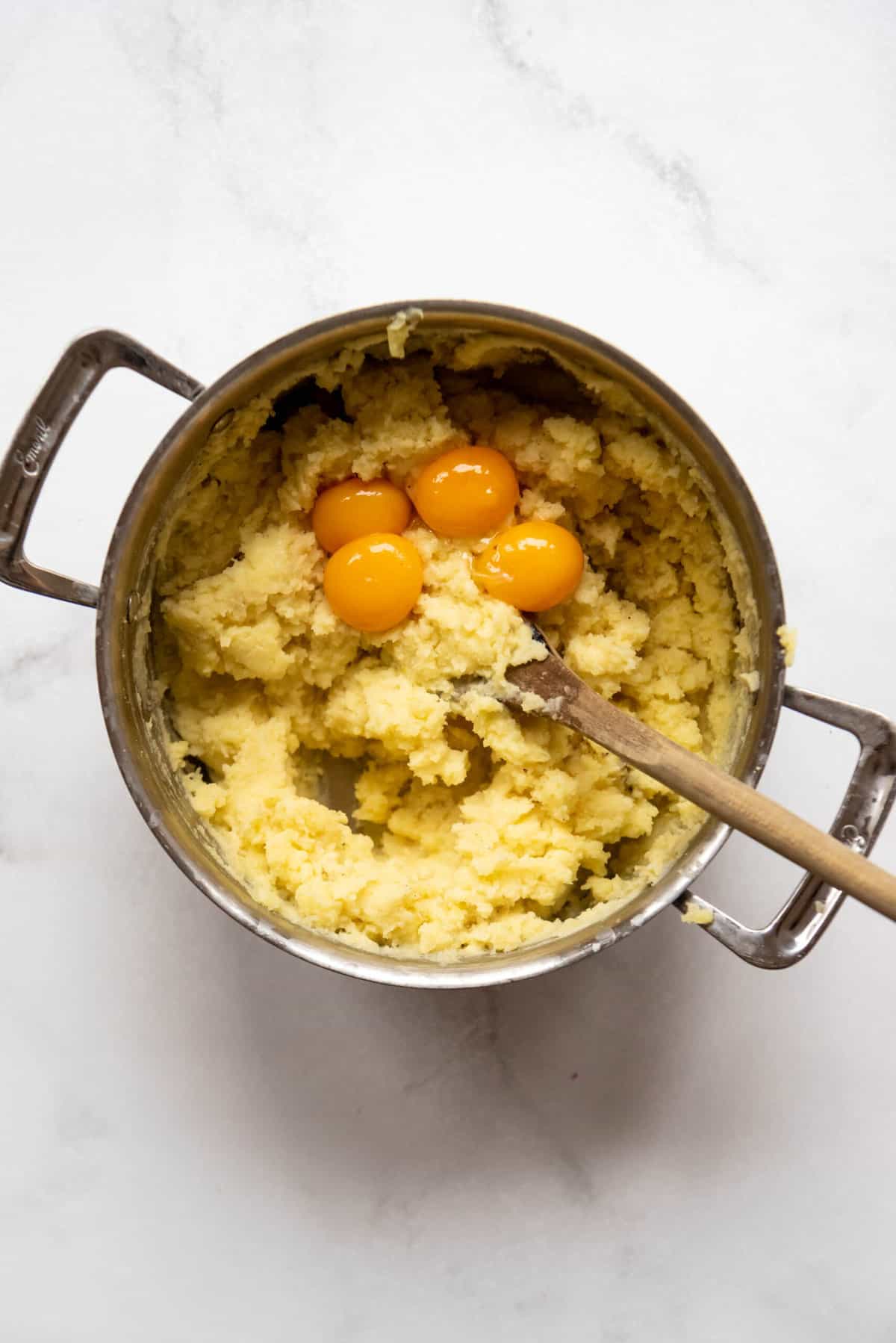 Adding egg yolks to creamy mashed potatoes to make Duchess potatoes.
