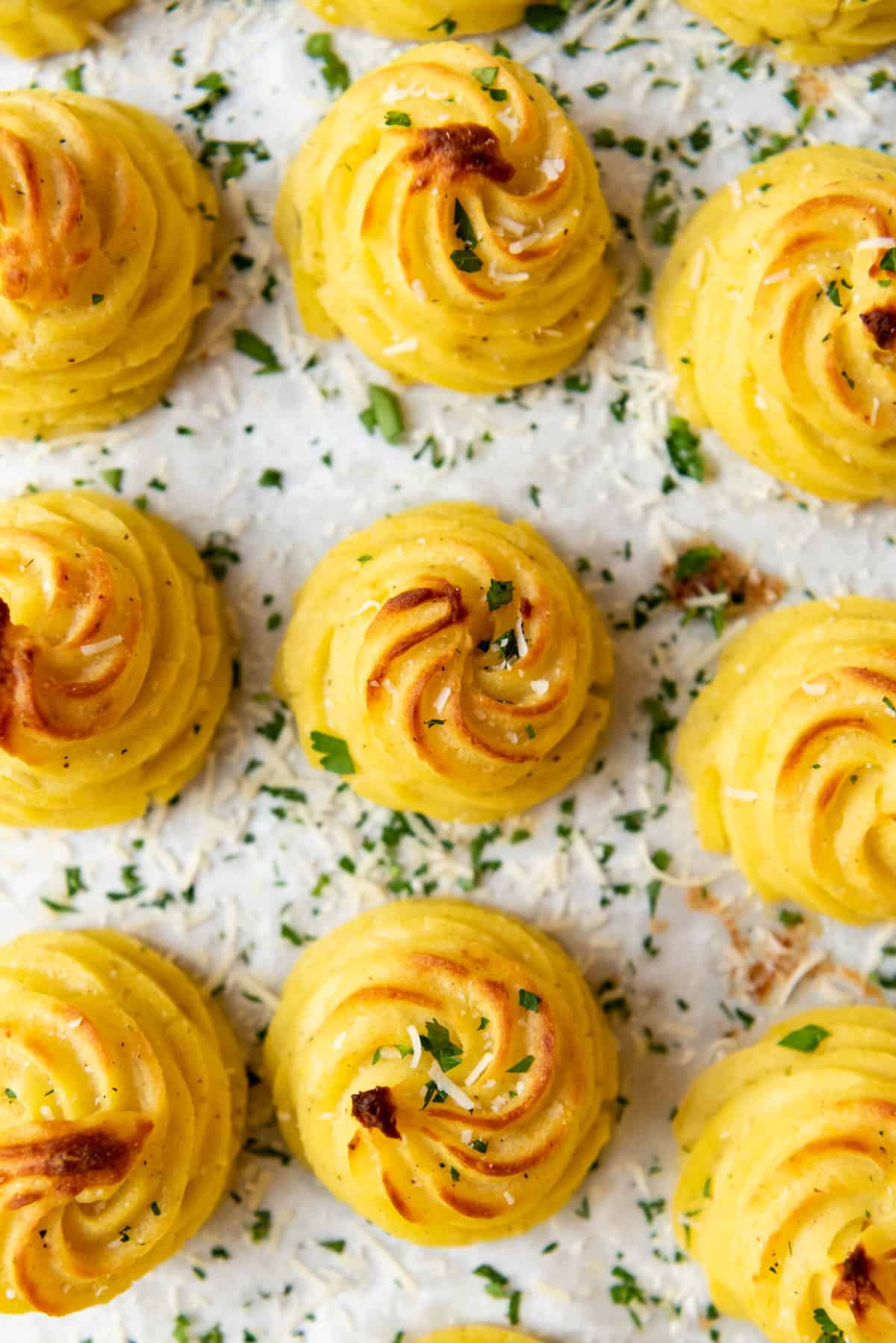 A close image of swirled duchess potatoes with golden brown tops.