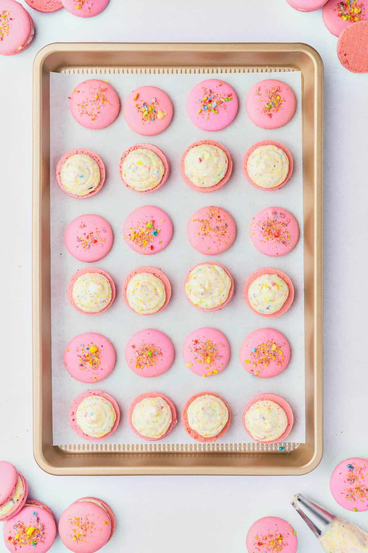 Buttercream frosting piped onto pink macarons.