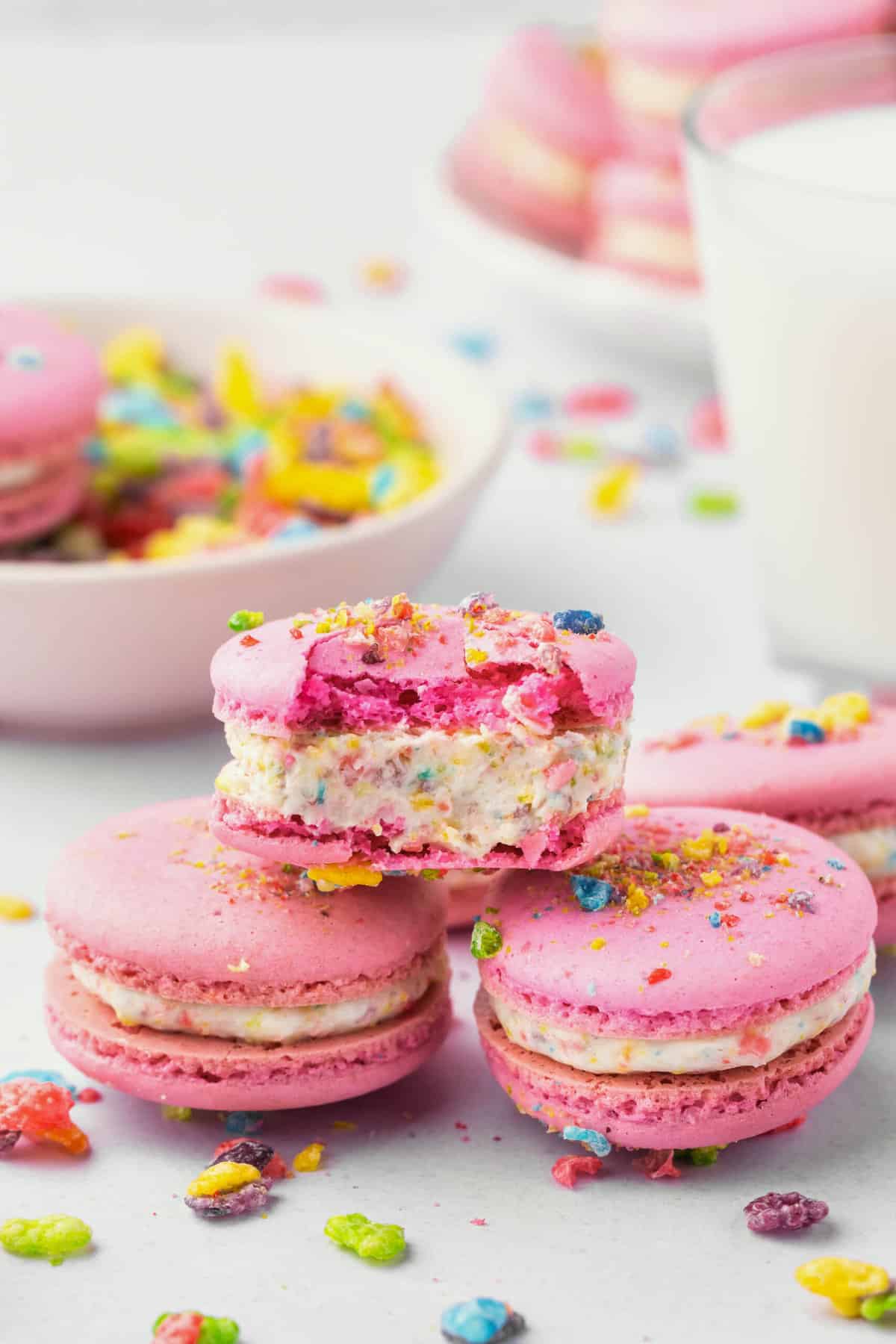 A close image of fruity pebbles macarons with a bite taken out of the top one.