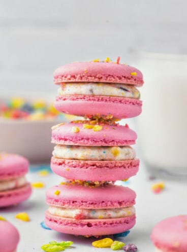 Three fruity pebbles macarons stacked on top of each other in a tower.