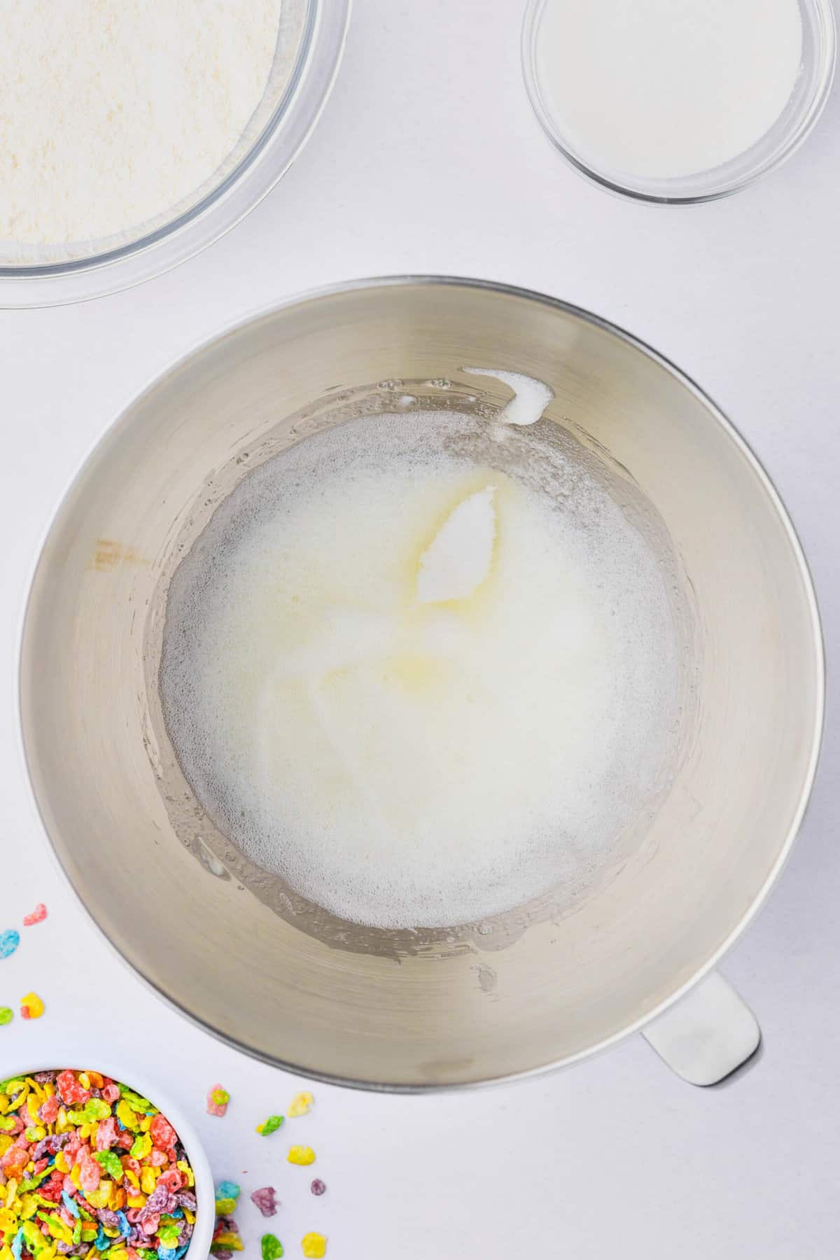 Foamy egg whites in a metal mixing bowl.