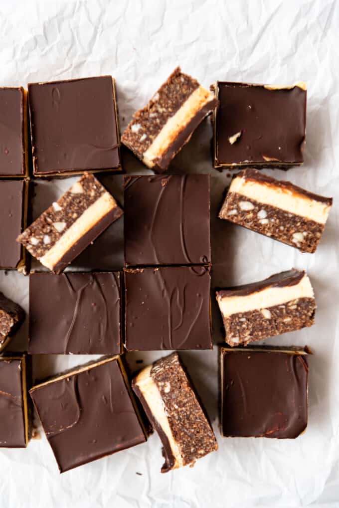 Nanaimo bars arranged haphazardly on crumpled white parchment paper.