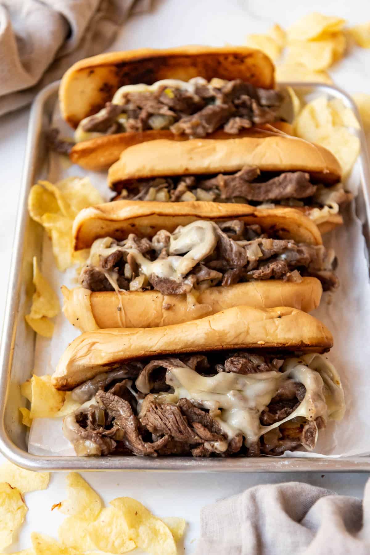 A baking sheet filled with Philly cheese steaks.