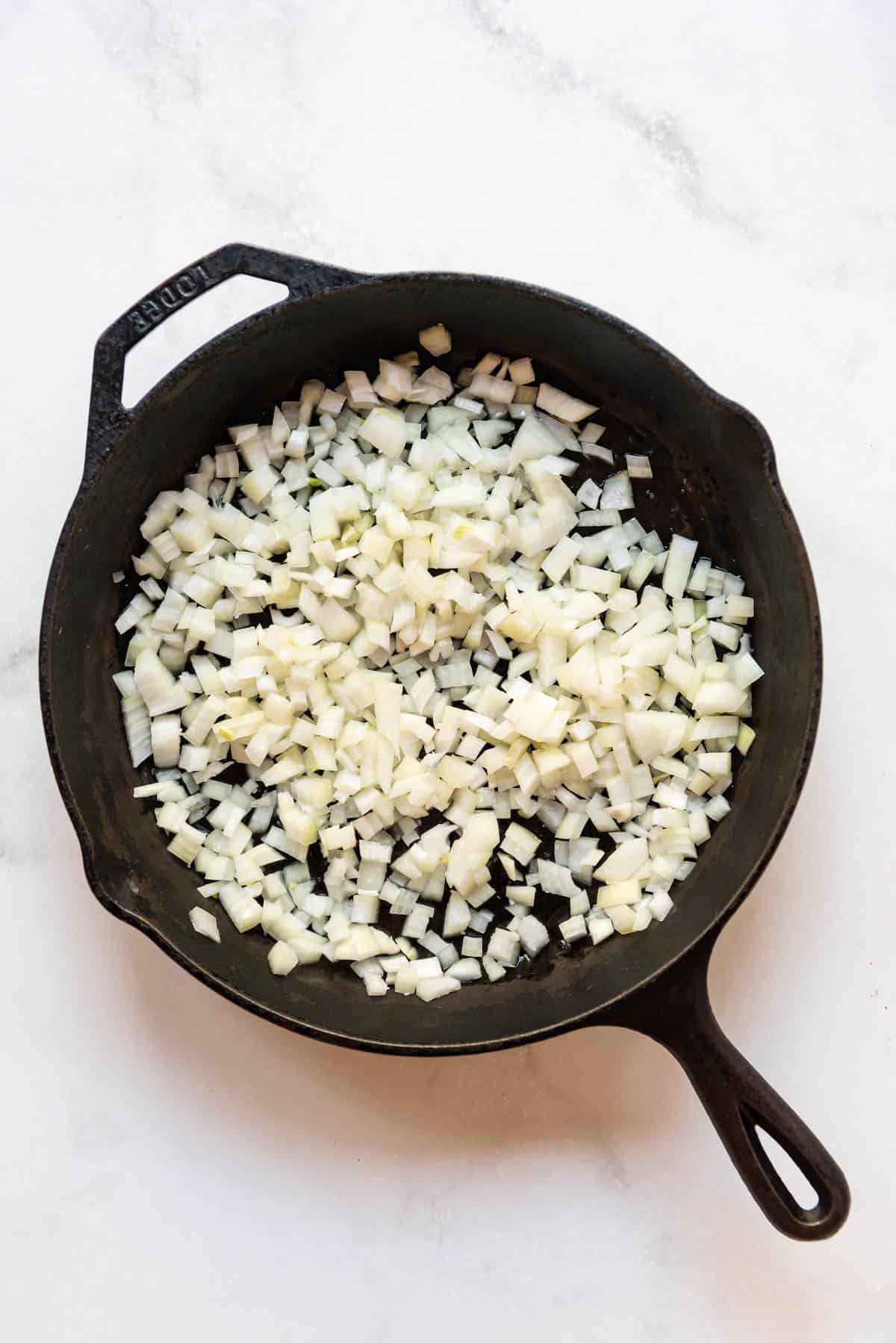 Diced onions in a large cast iron skillet.