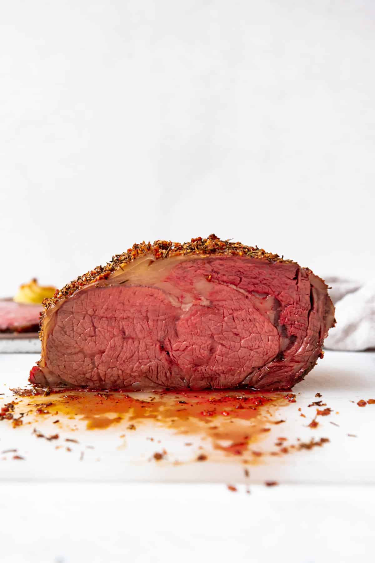 A medium-rare smoked prime rib roast on a cutting board with its juices.