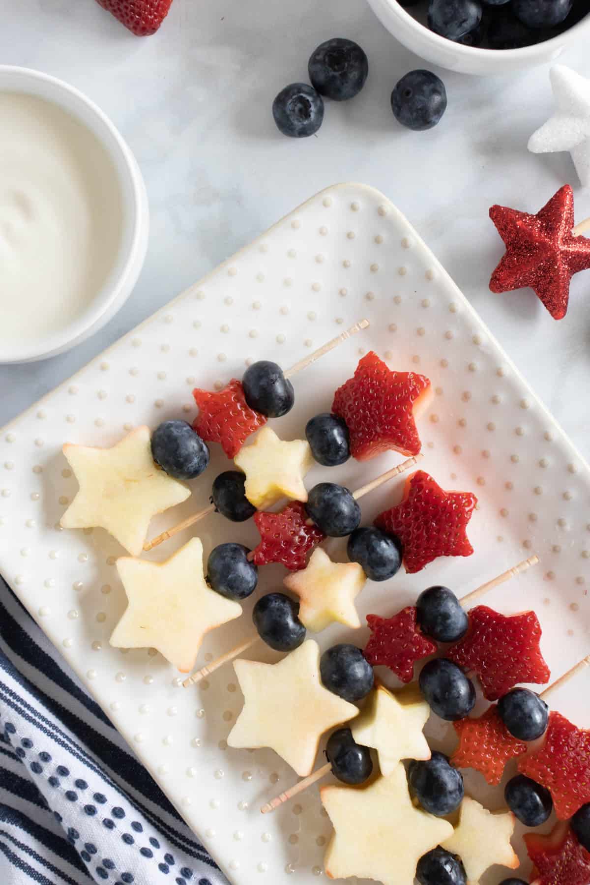 A plate of healthy 4th of July snacks made with fruit in star shapes.