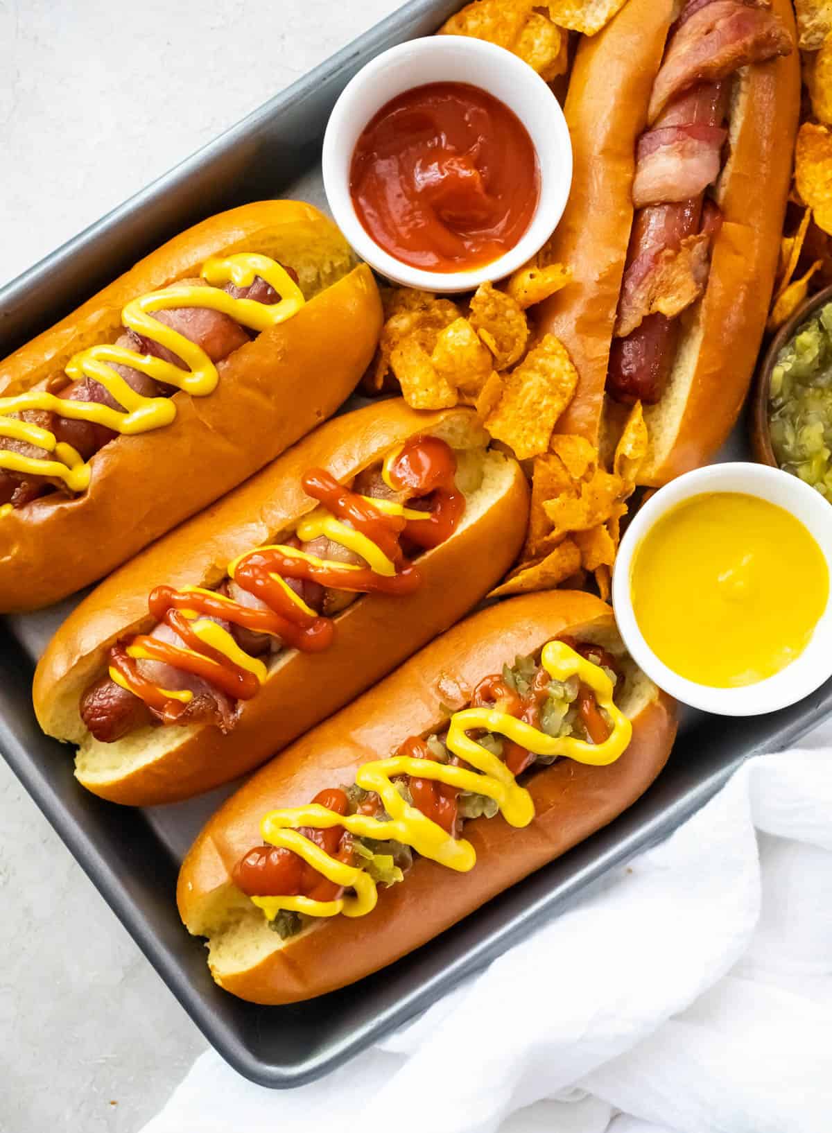 An overhead image of bacon wrapped hot dogs with ketchup and yellow mustard.