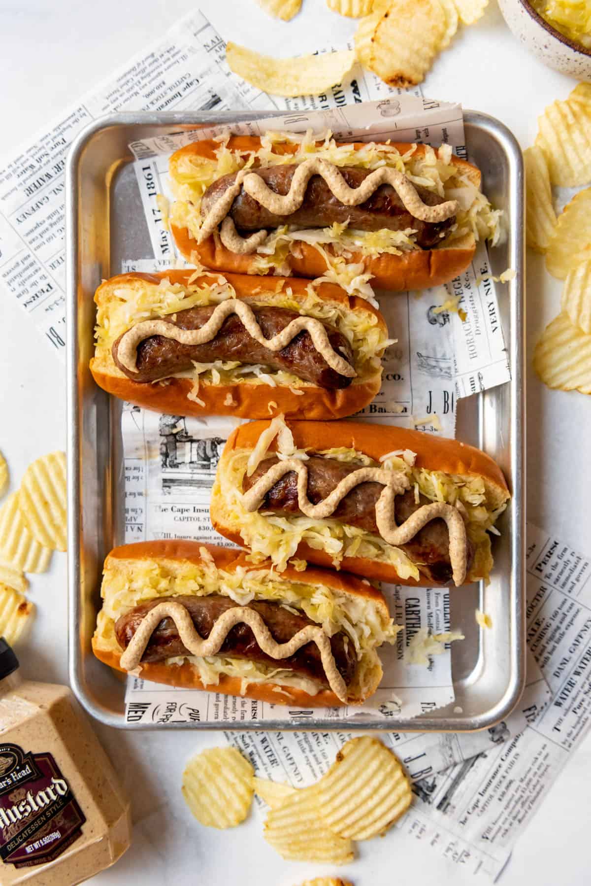 Top view of Air fryer brats on buns with mustard and sauerkraut.