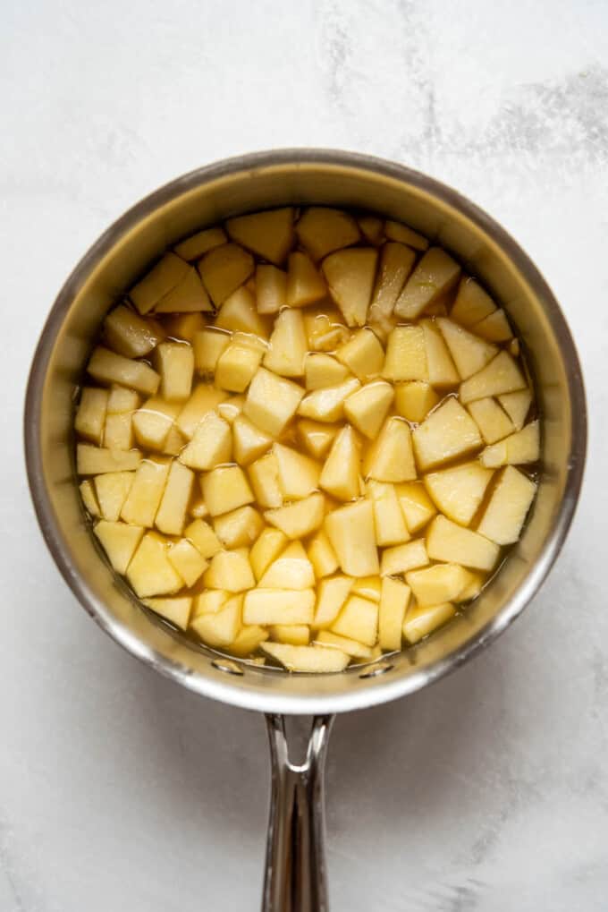 Diced apples in a saucepan with apple cider.