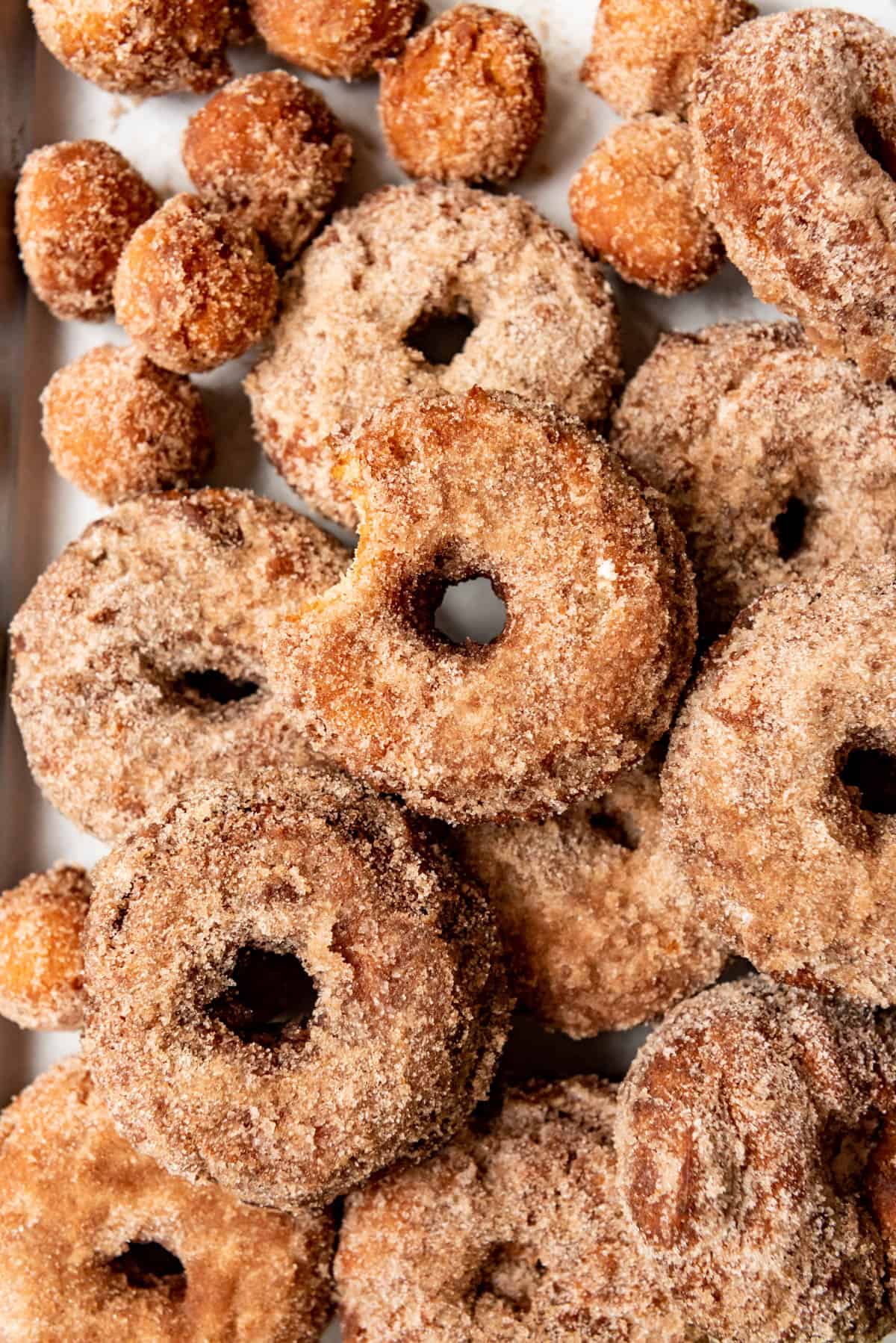 An apple cider donut with a bite taken out of it surrounded by other donuts.