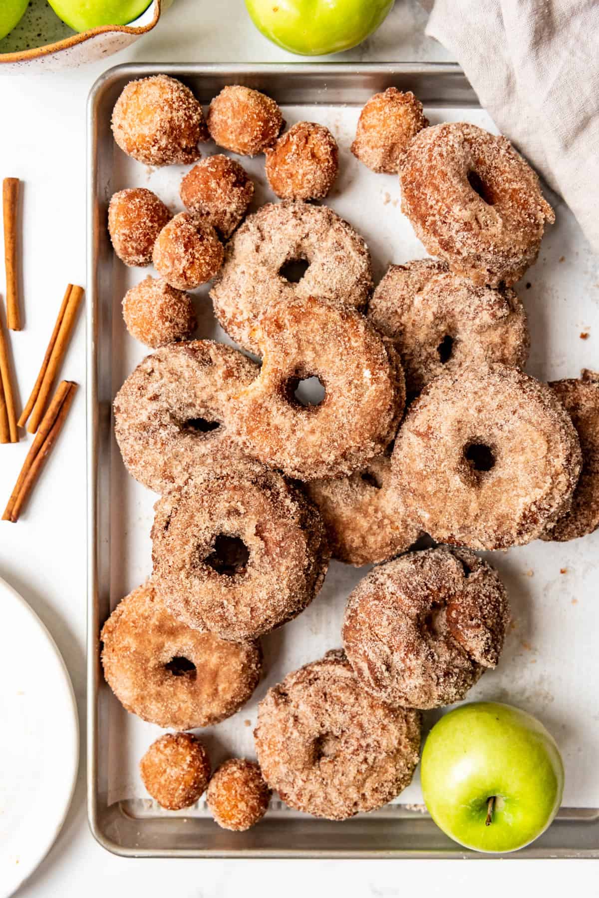 An overhead image of old-fashioned apple cider donuts on a baking sheet.