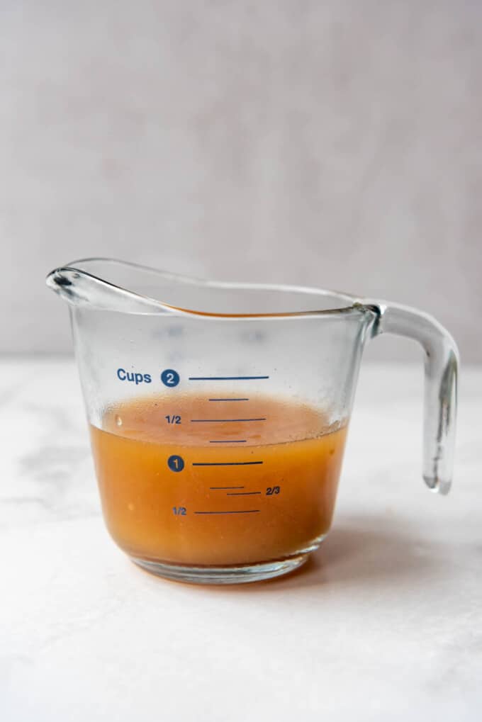 Reduced apple cider in a glass measuring cup.