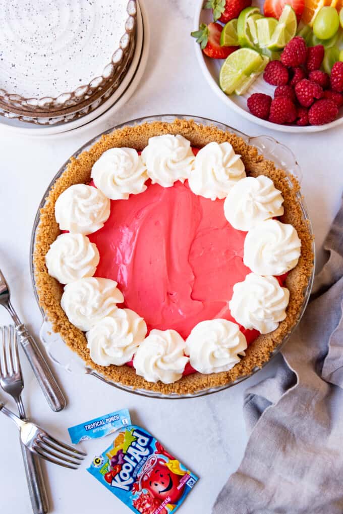 Adding piped swirls of whipped cream to a kool-aid pie.