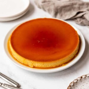 Close up of a whole Mexican flan on a white plate.