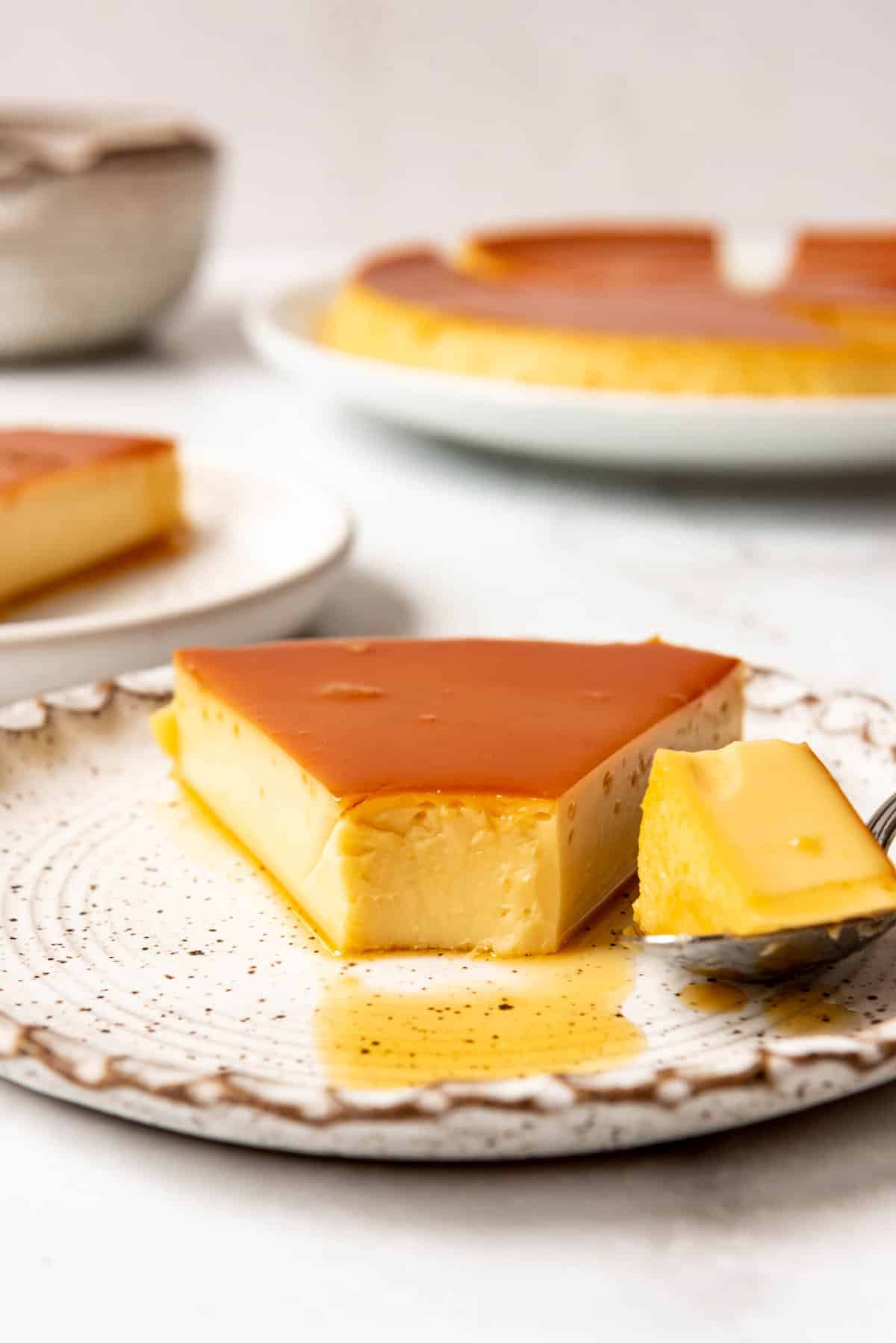 Close up of a slice of flan with a bite taken out of it. 
