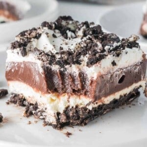 A slice of Oreo dessert on a plate with a bite taken out of it.