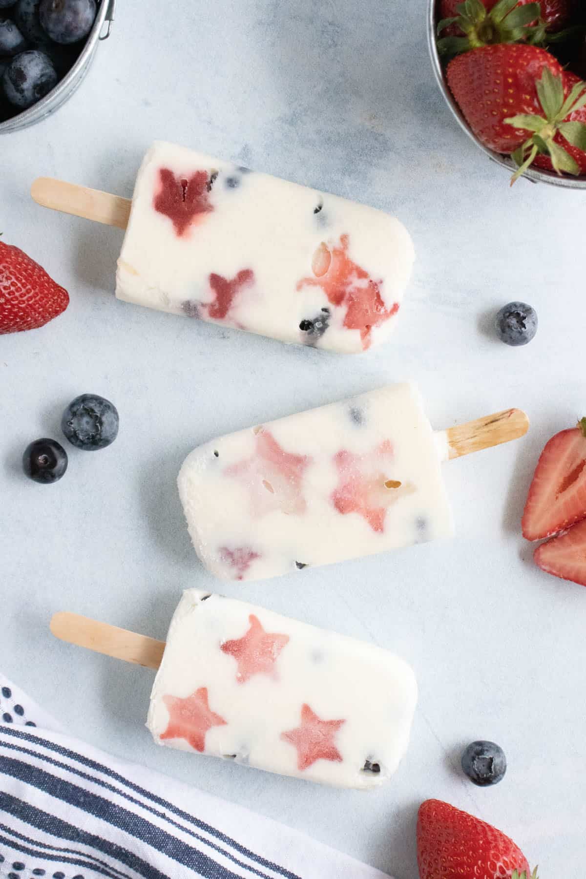 Three fruit and yogurt popsicles in patriotic red white and blue colors.