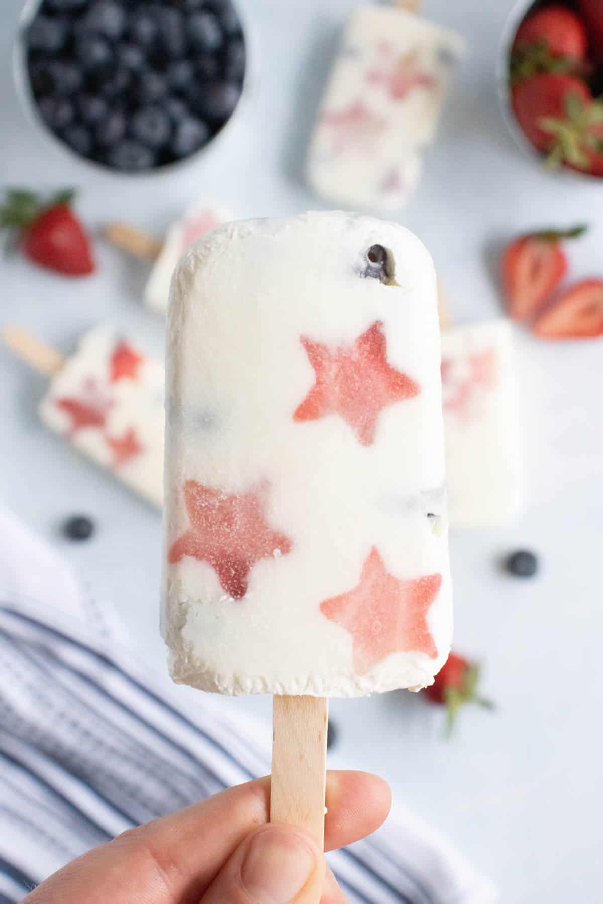 A hand holding a patriotic popsicle made with fruit and yogurt.