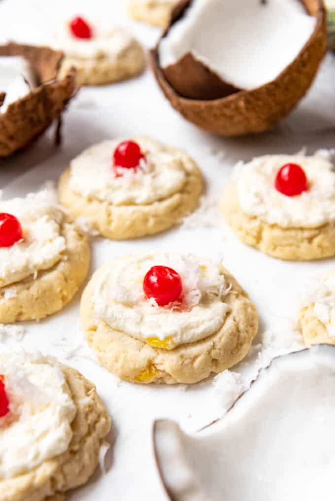 Frosted pina colada cookies with maraschino cherries on top.
