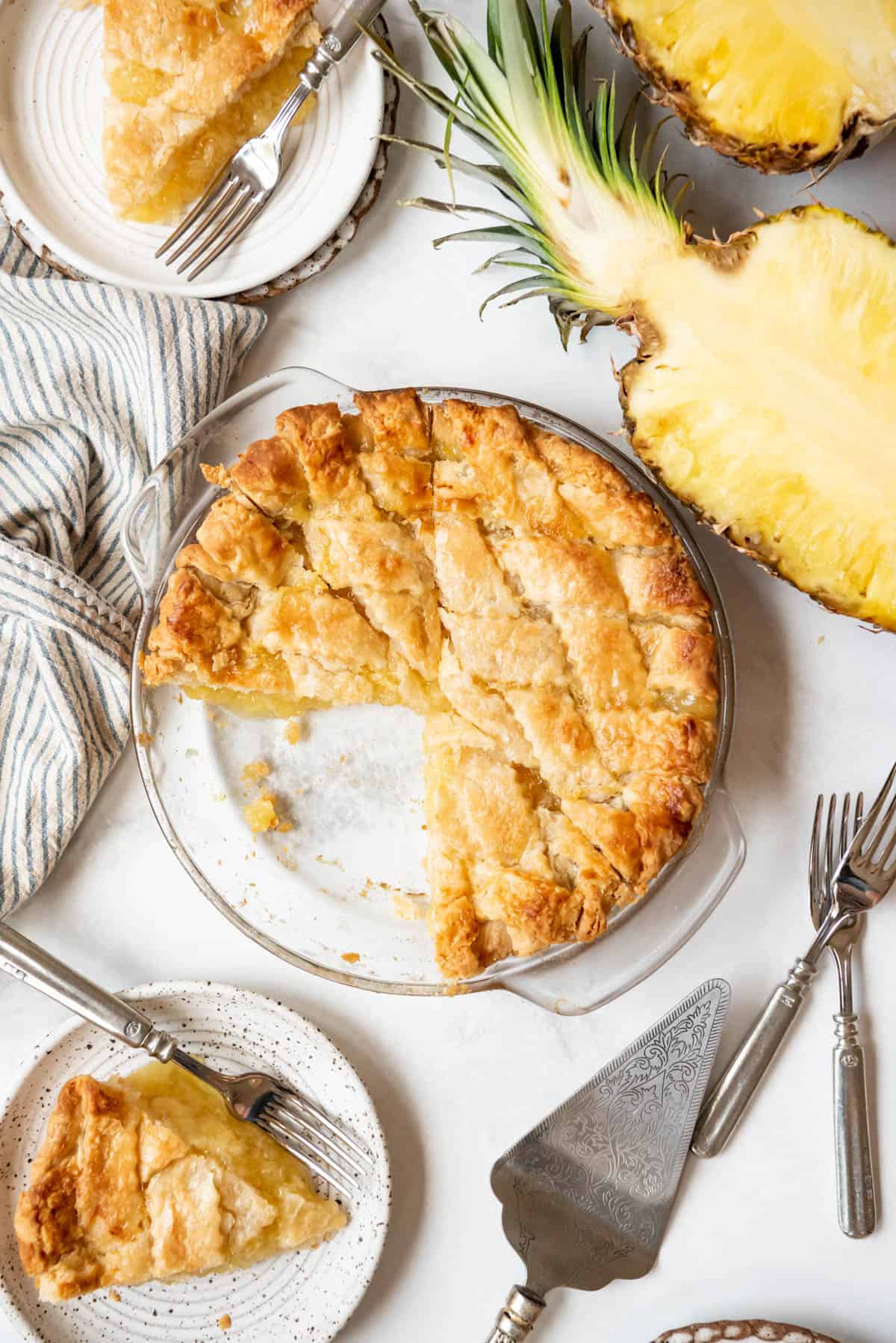 An overhead image of a double crust pineapple pie next to a sliced pineapple half.