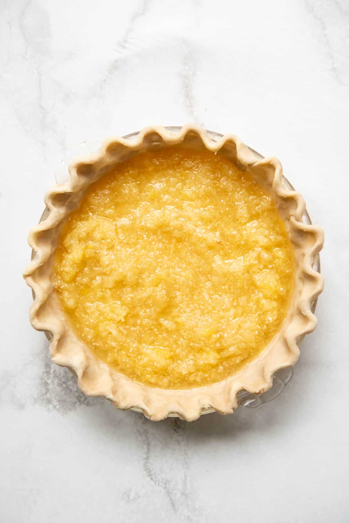 Pineapple pie filling in an unbaked pie crust.