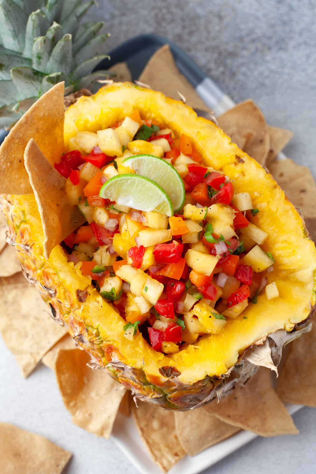 Pineapple salsa in a hollowed out pineapple with corn tortilla chips around it.