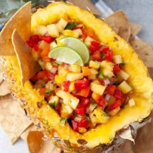 Pineapple salsa in a hollowed out pineapple with corn tortilla chips around it.