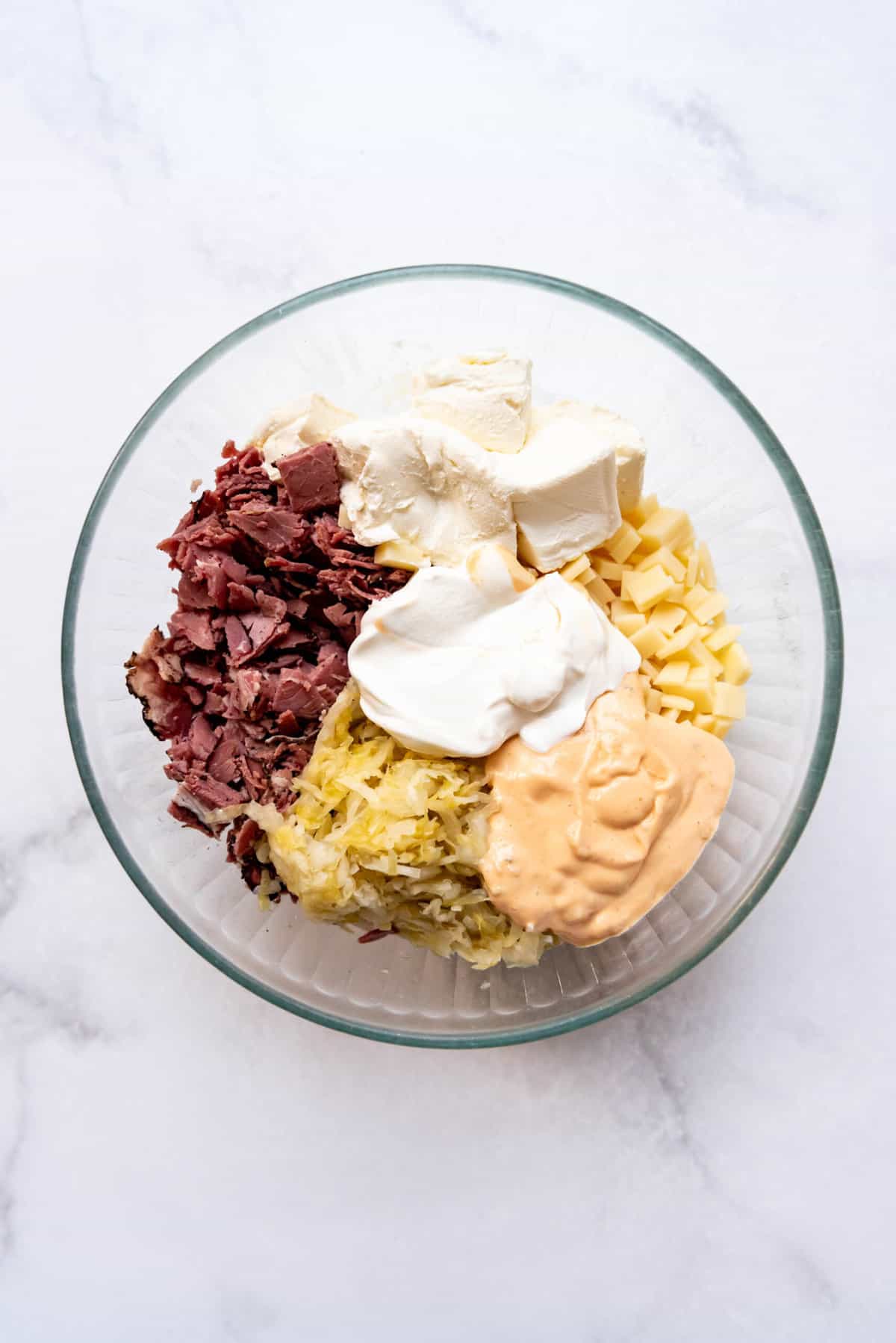All of the ingredients for making reuben dip in a large mixing bowl.