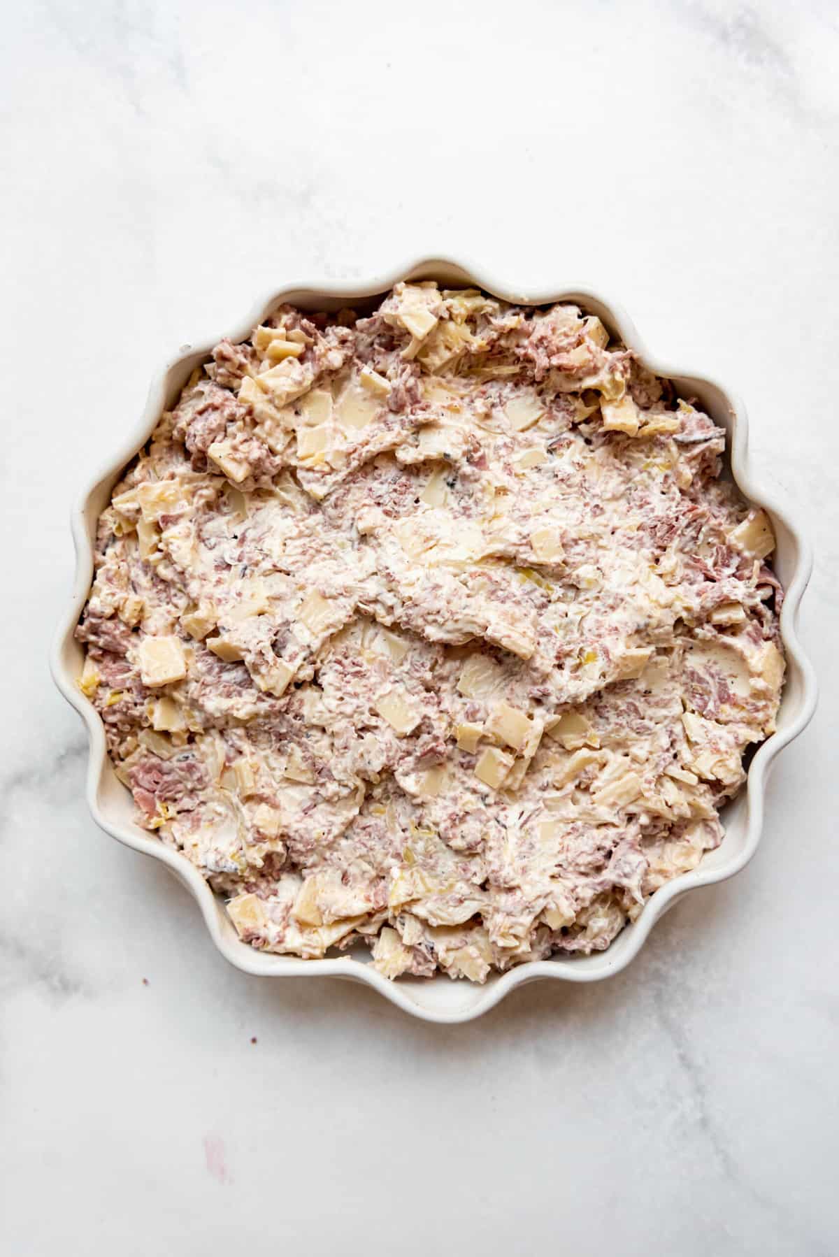 Reuben dip spread into a pie plate before being baked in the oven.