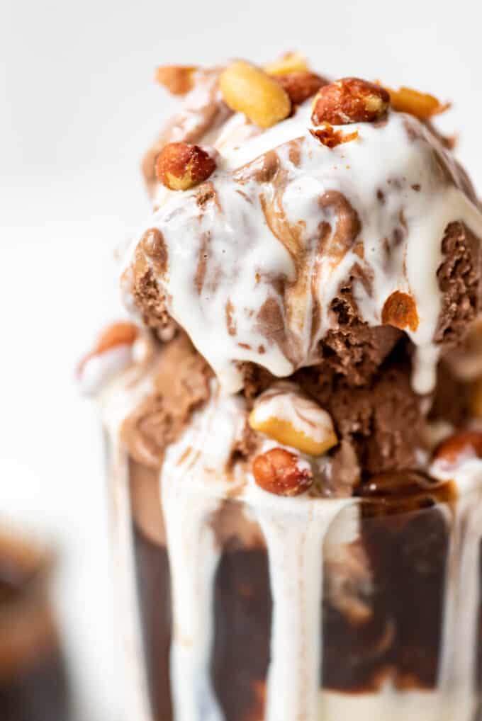 A close image of an ice cream sundae with chocolate ice cream, marshmallow sauce, and spanish peanuts.