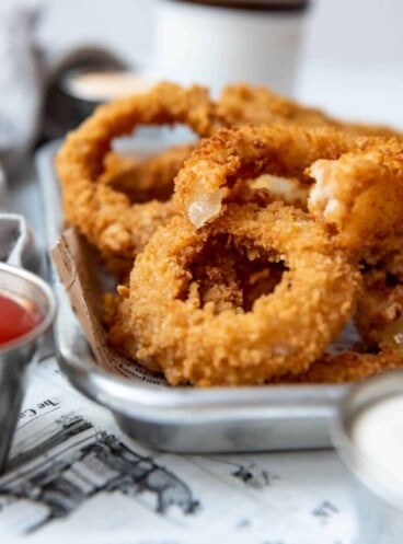 An onion ring with a bite taken out of it on top of more onion rings.
