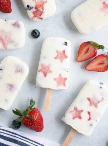 Patriotic fruit and yogurt popsicles with strawberries and blueberries.