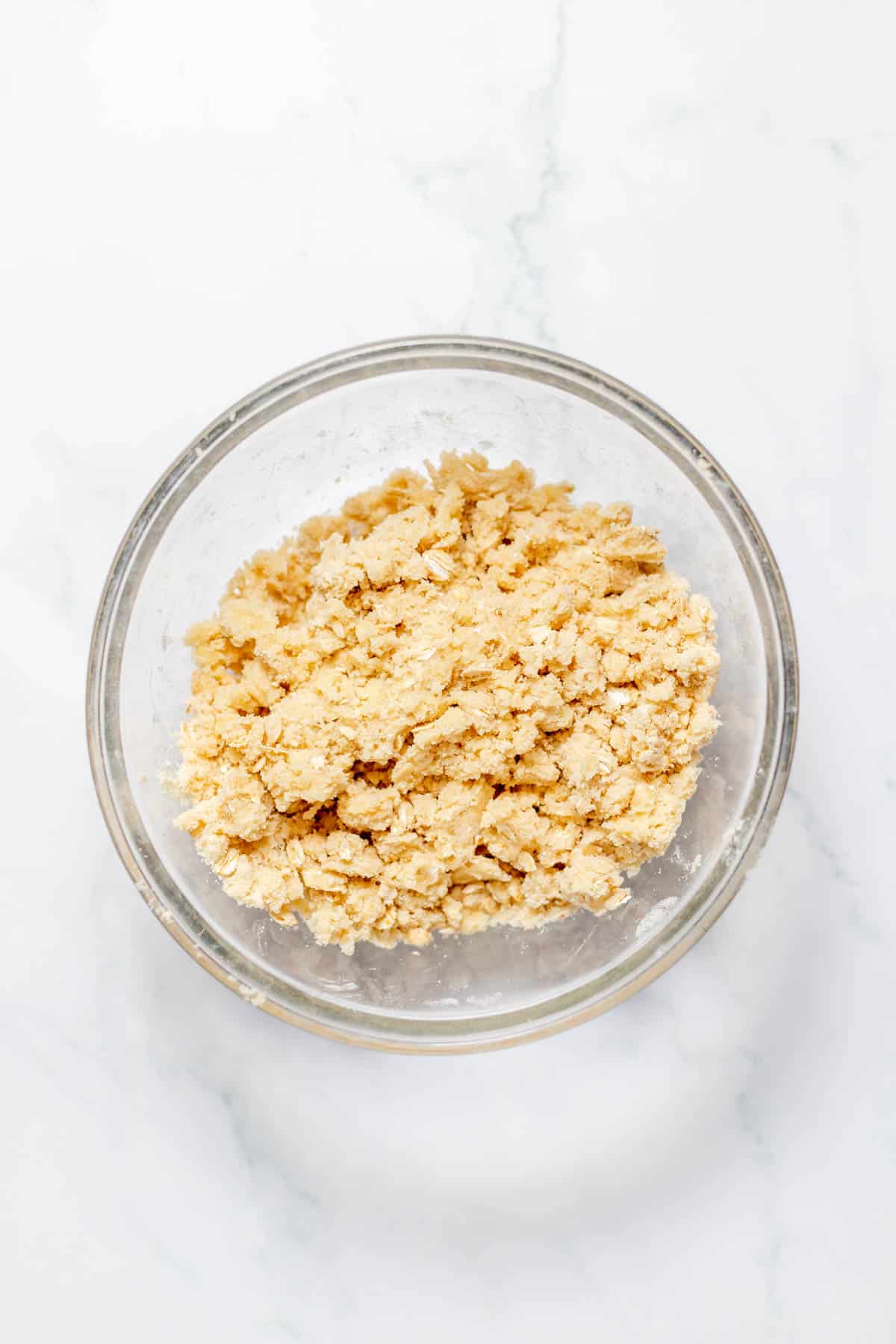 A streusel crumble mixture in a glass mixing bowl.