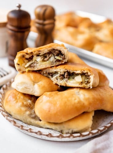 Homemade runzas on a plate with one of them cut in half to show the filling inside.