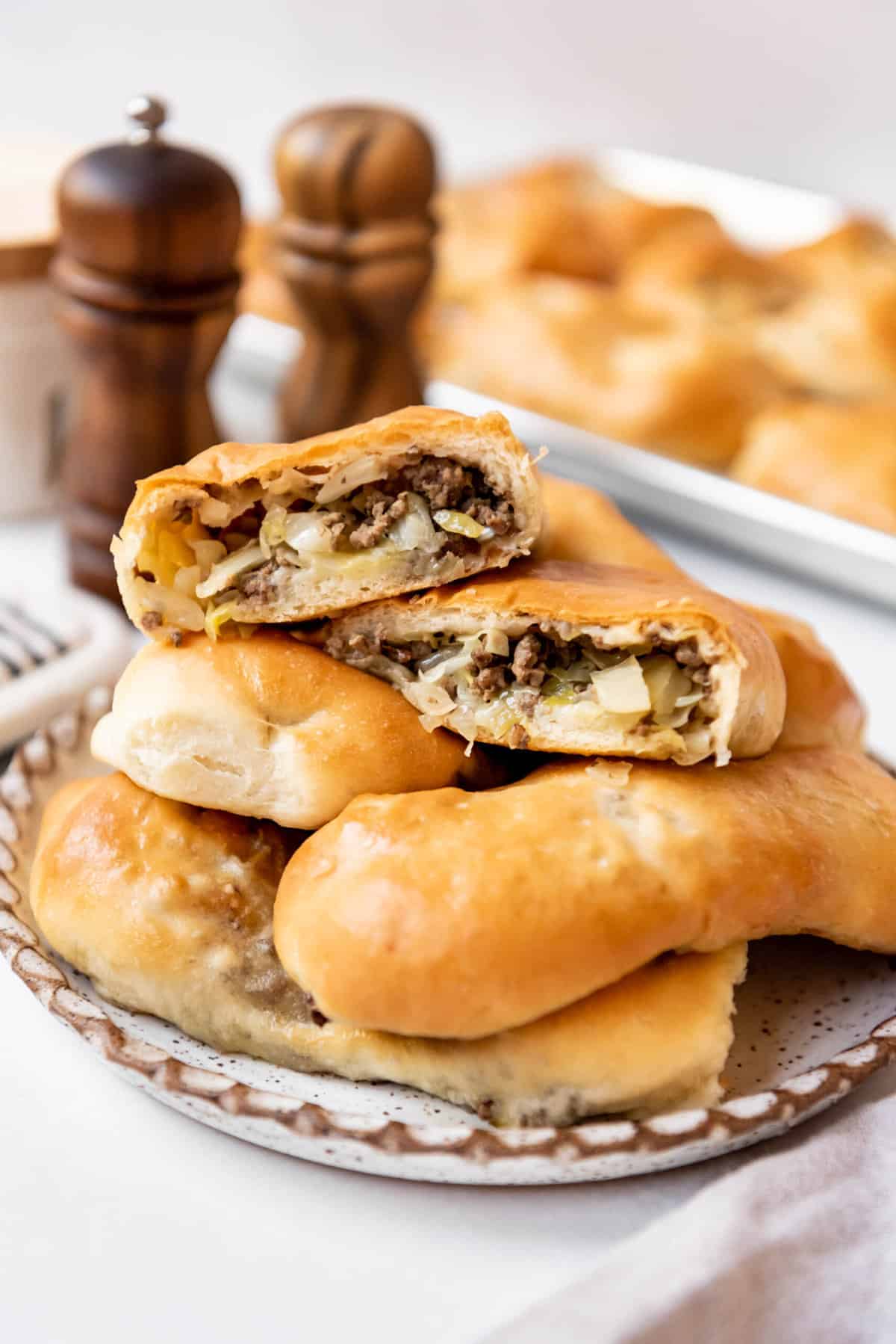 Homemade runzas on a plate with one of them cut in half to show the filling inside.