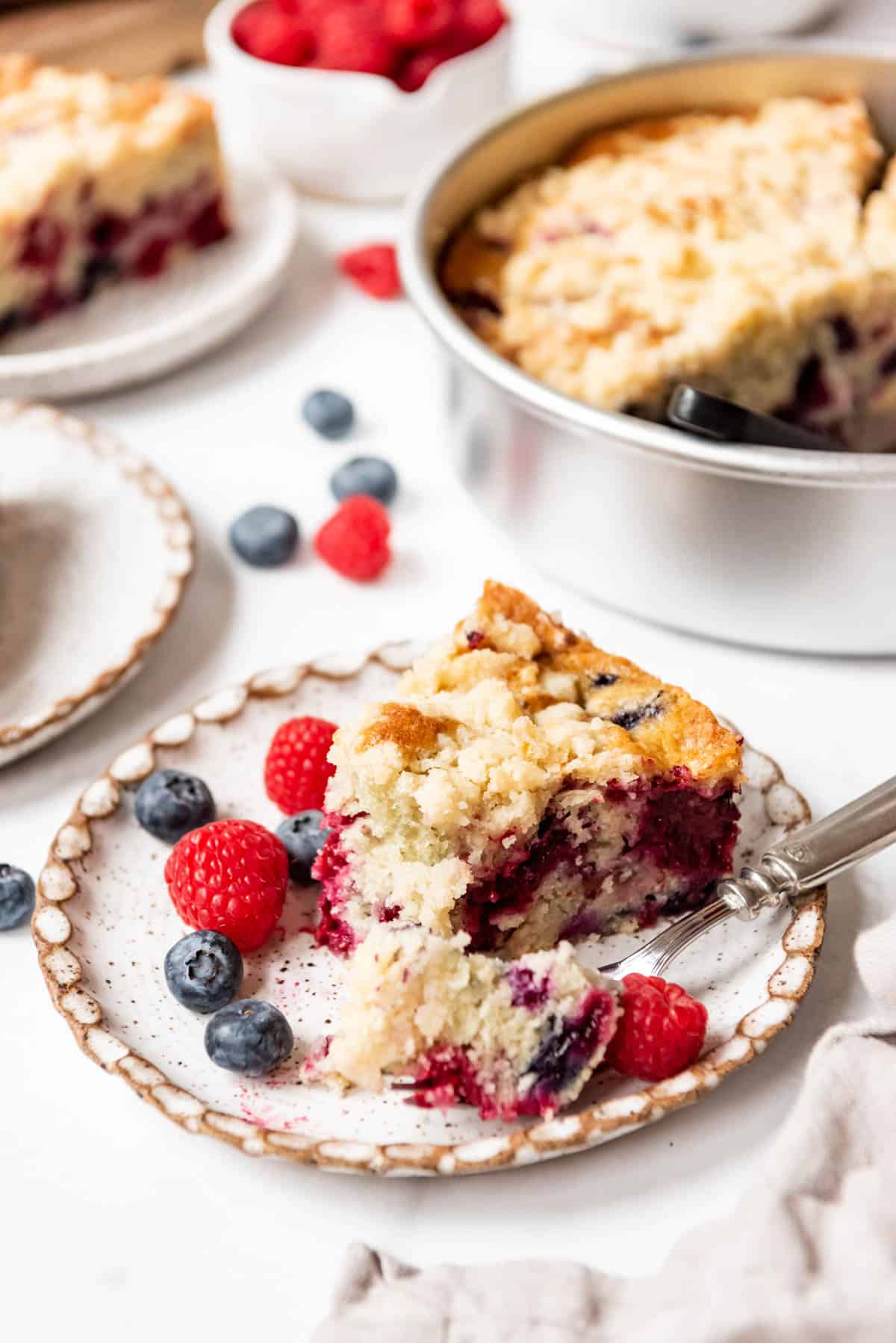 A slice of mixed berry breakfast cake with a bite taken out of it.