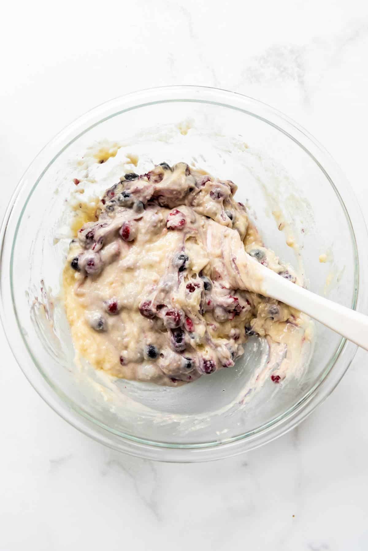 Gently stirring frozen mixed berries into muffin batter.