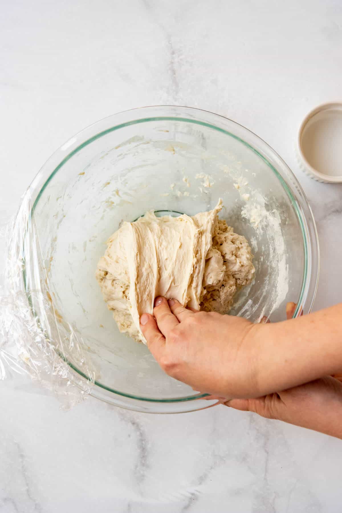 Pulling sourdough bread dough on top of itself to finish a stretch and fold.