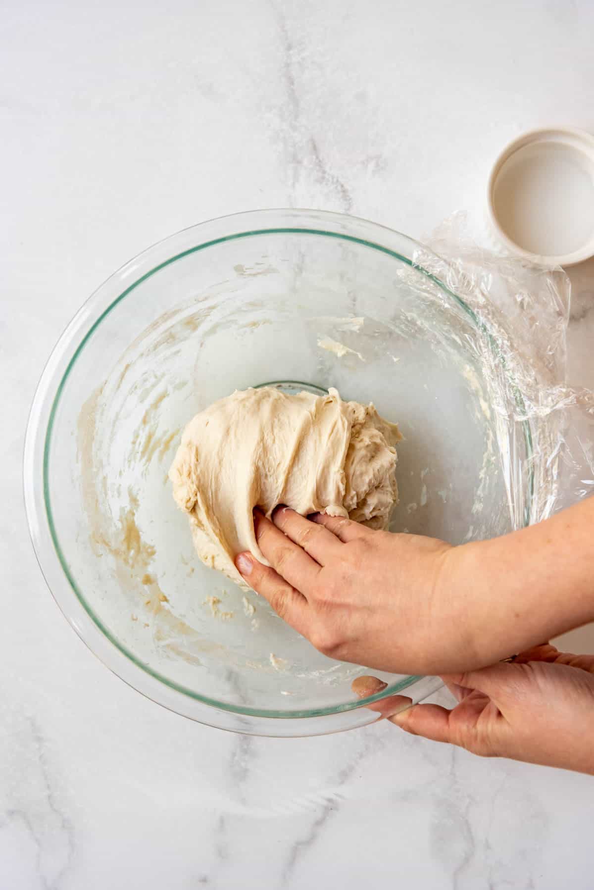 Pulling sourdough bread dough on top of itself to finish a stretch and fold.