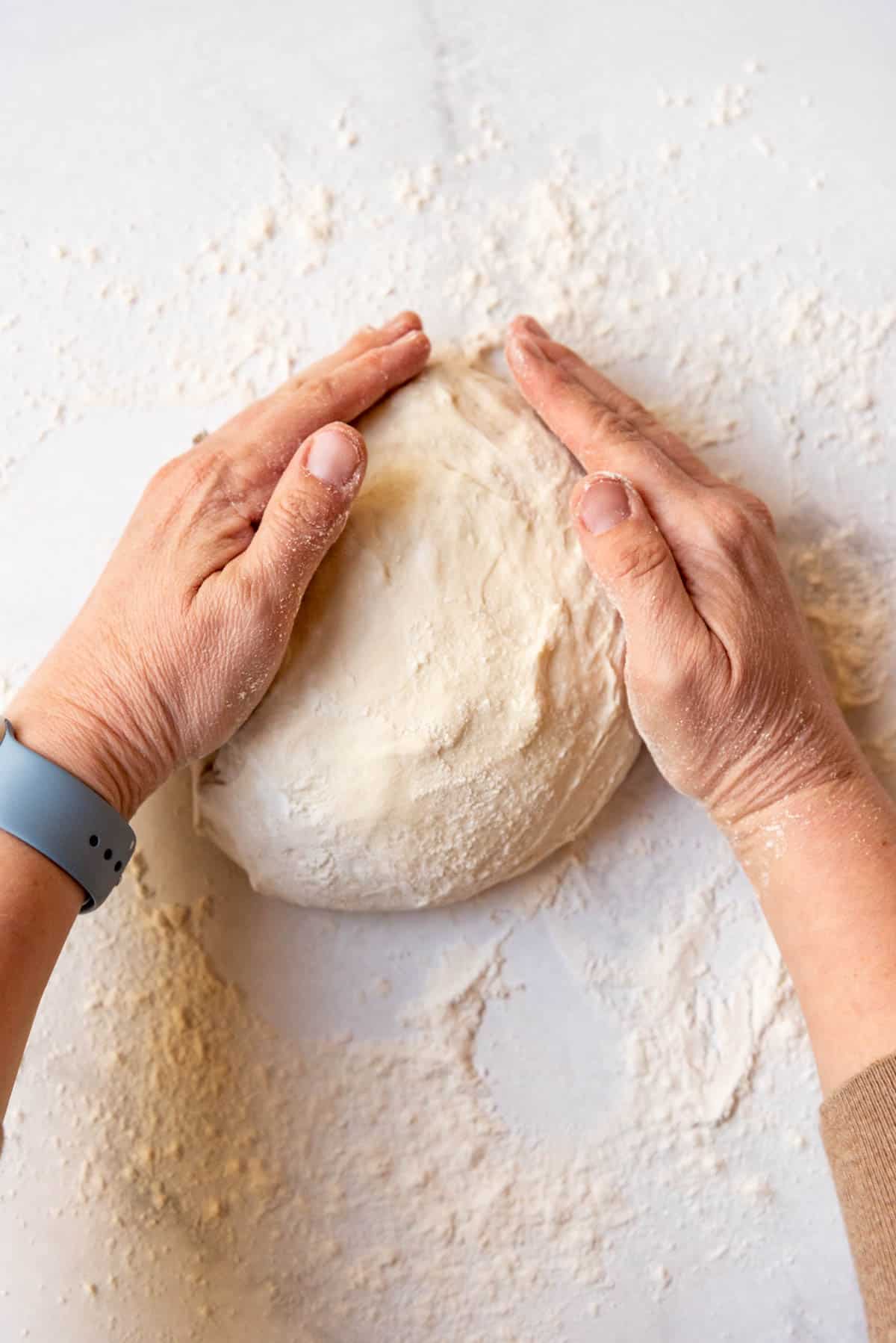 Shaping a ball of sourdough bread dough.