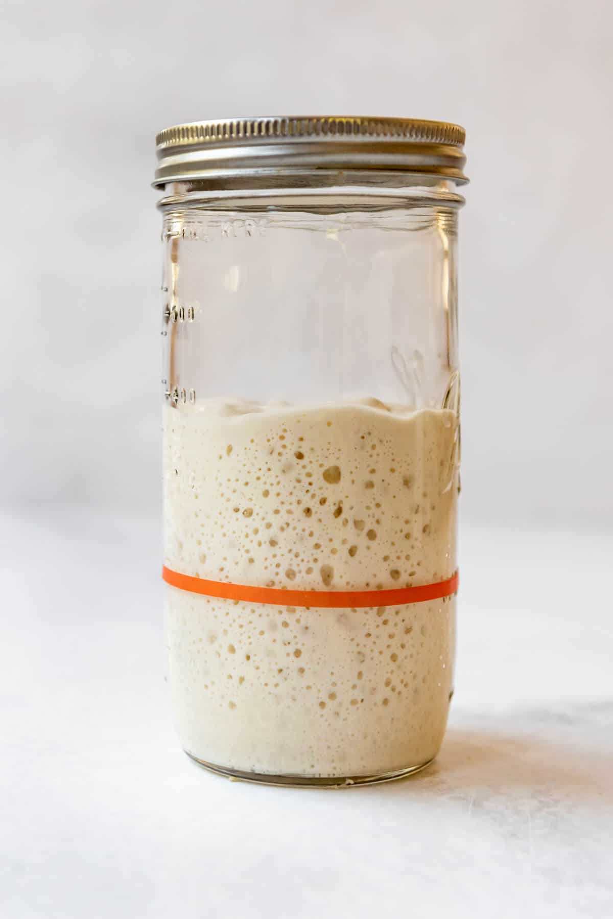 Sourdough starter that has been fed and bubbly in a glass jar.