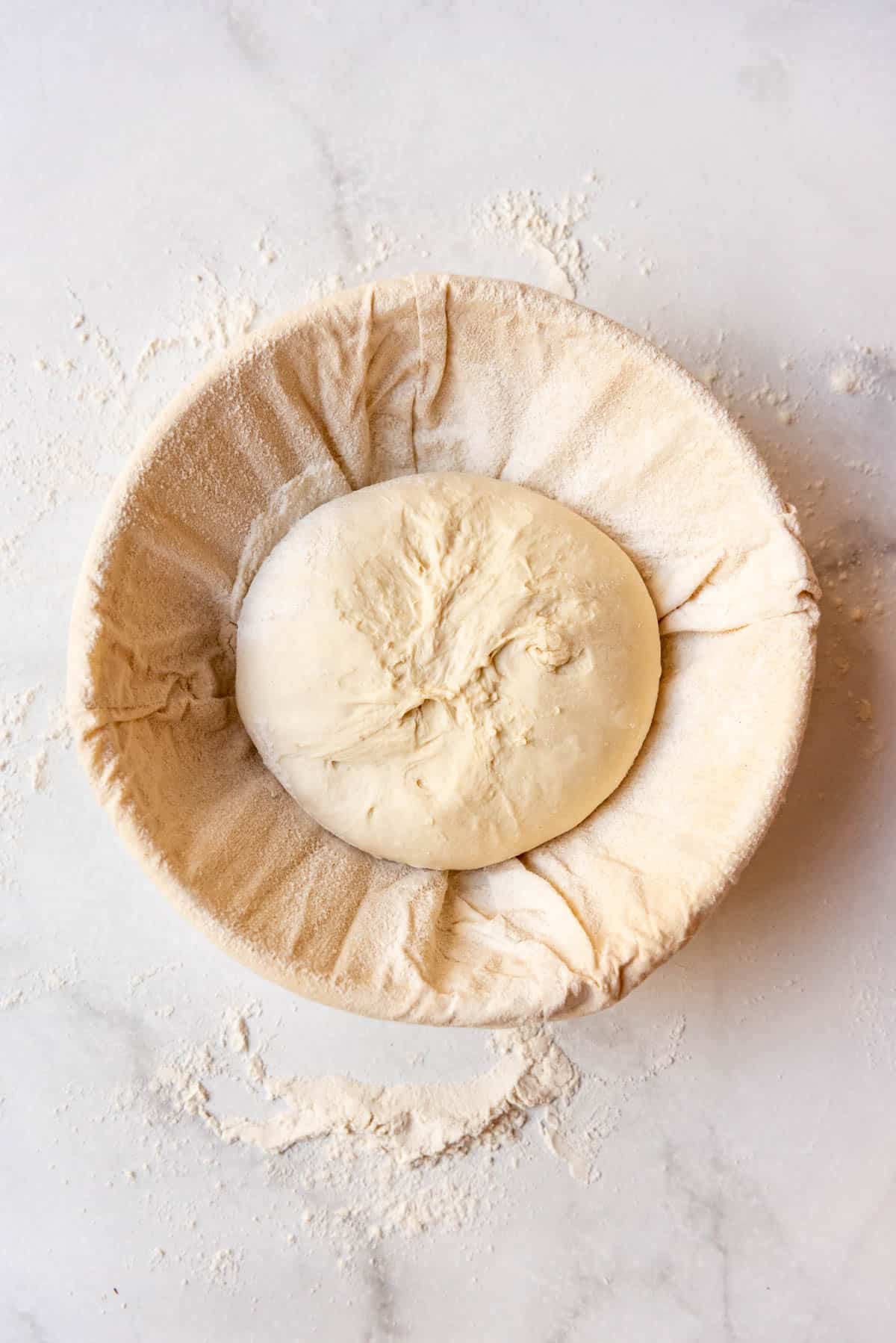 A ball of sourdough bread dough in a banneton basket.