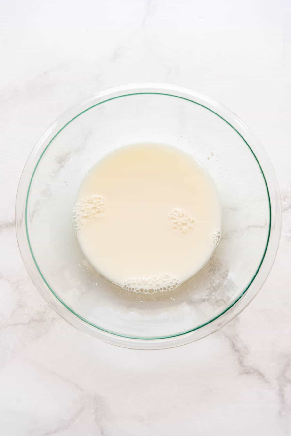 Water and natural yeast in a large glass bowl for making sourdough bread.