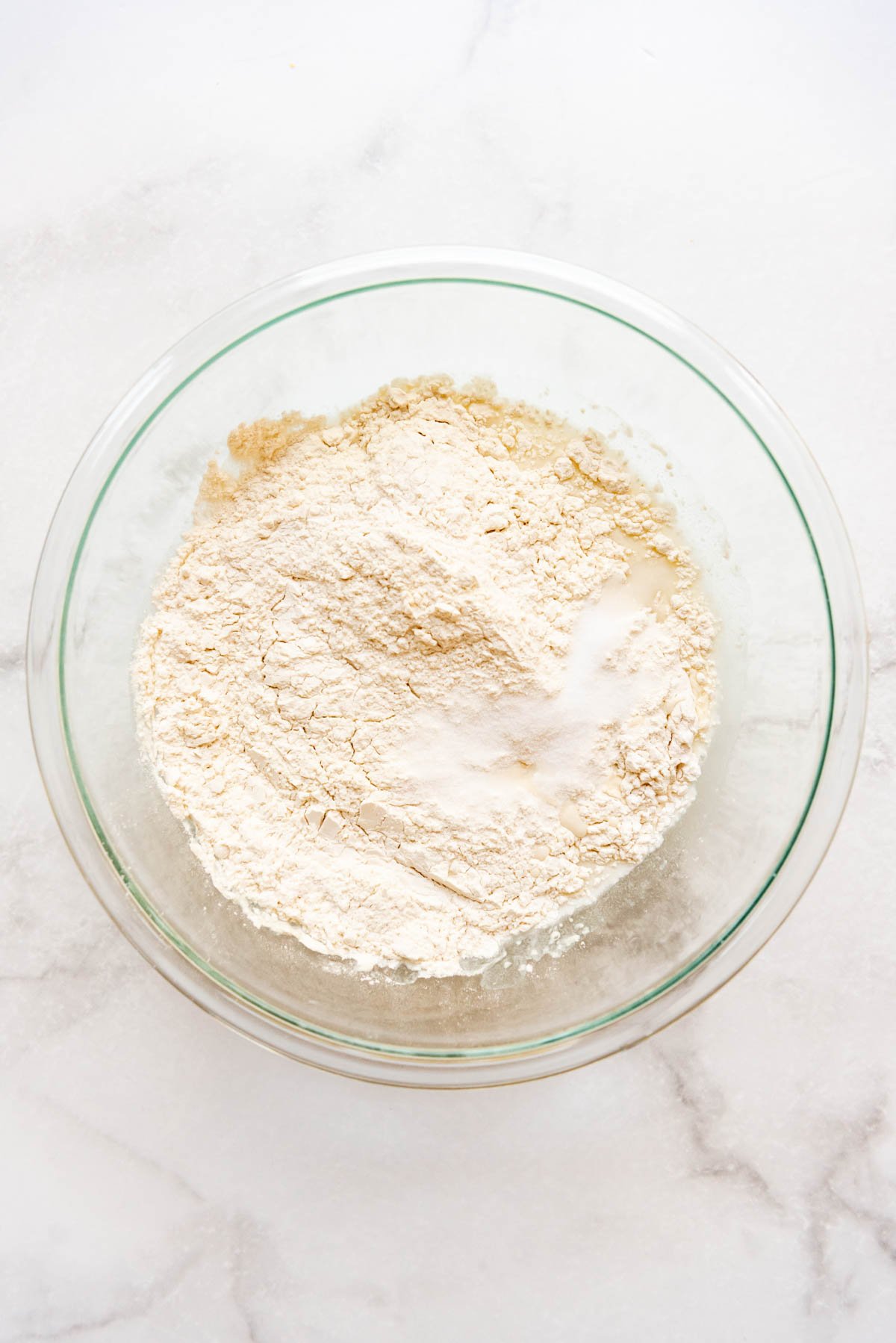 Adding flour and salt to a large glass bowl.