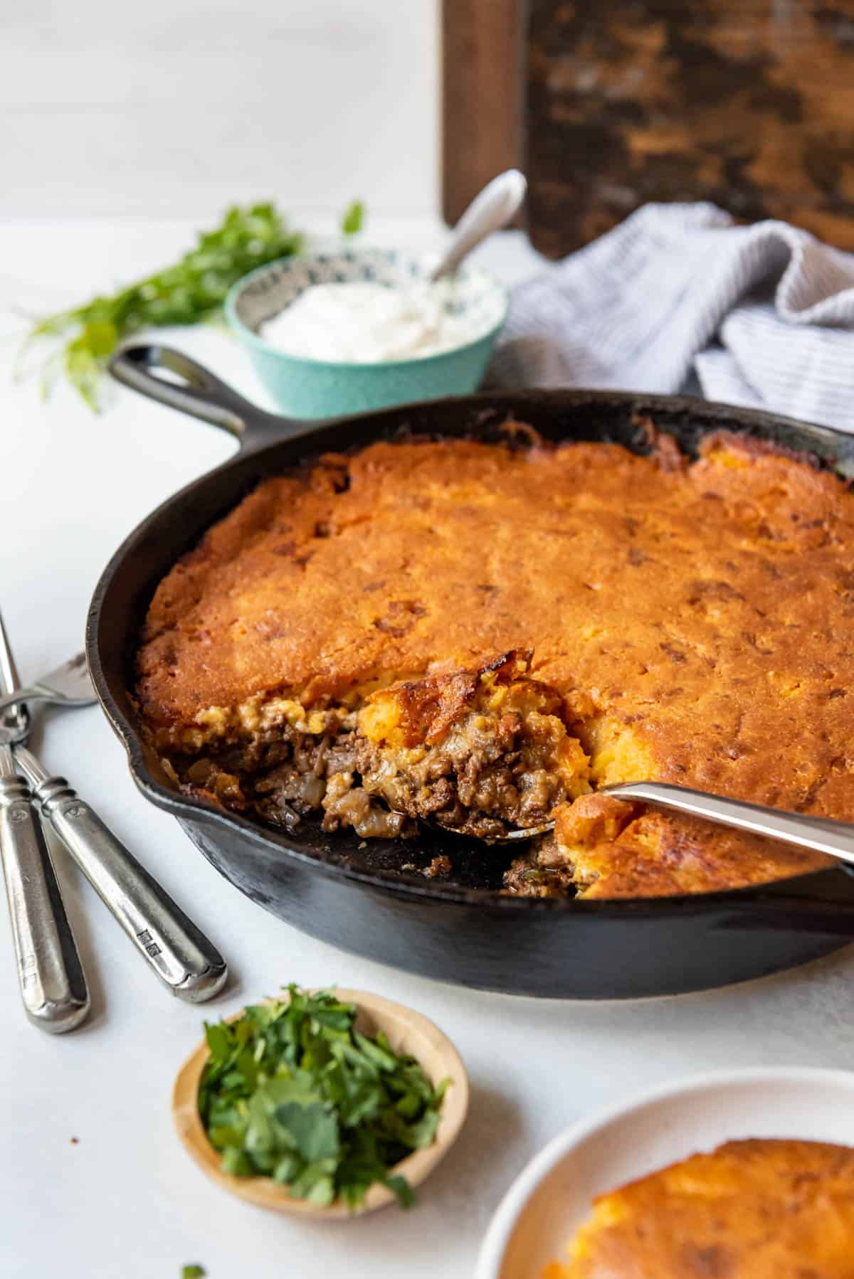 A serving spoon in a skillet full of tamale pie.