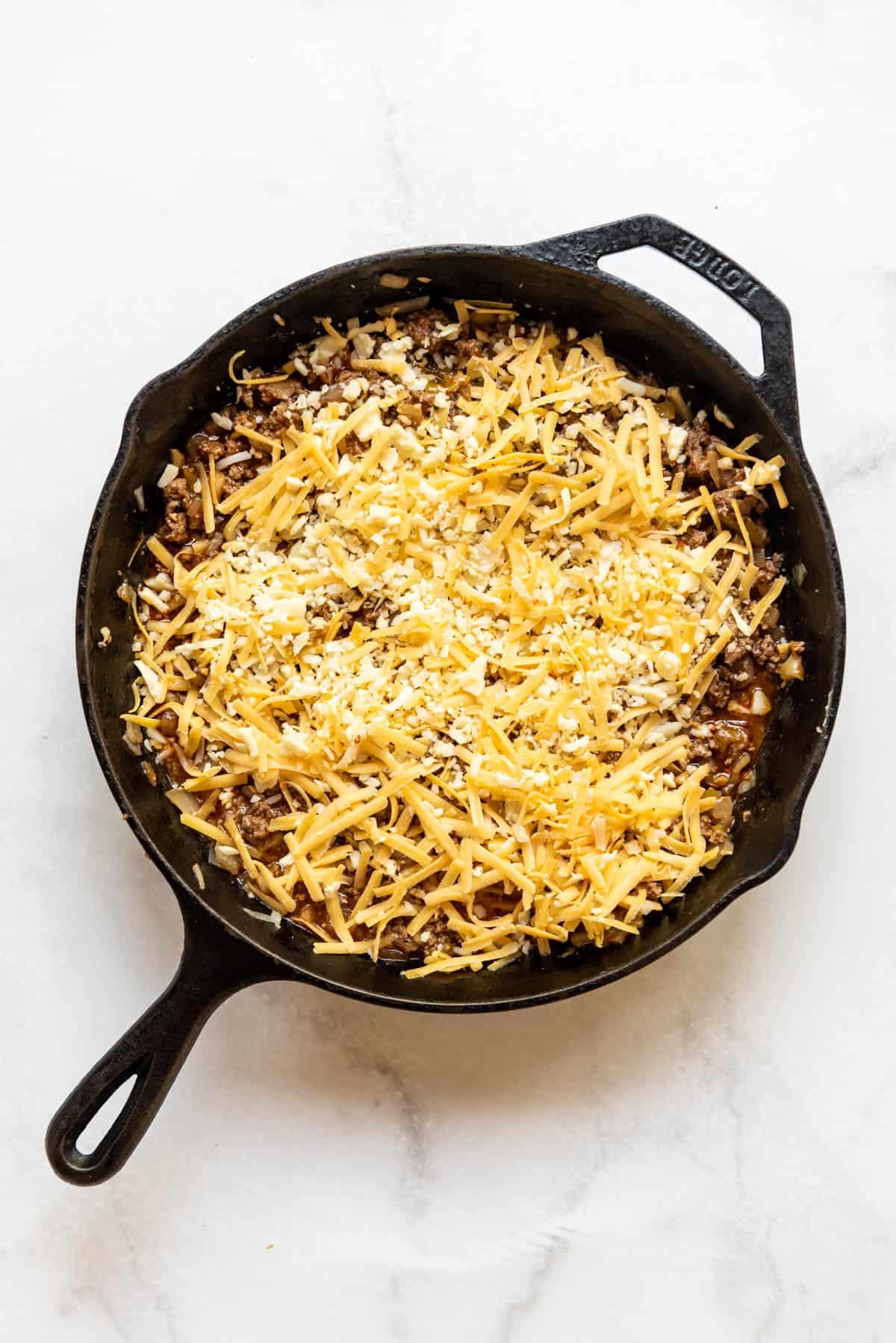Grated cheese sprinkled over ground beef tamale pie filling.
